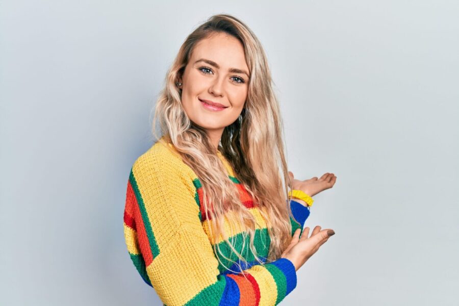 Beautiful young blonde woman wearing colored sweater inviting to enter smiling natural with open hand. standard repayment plan