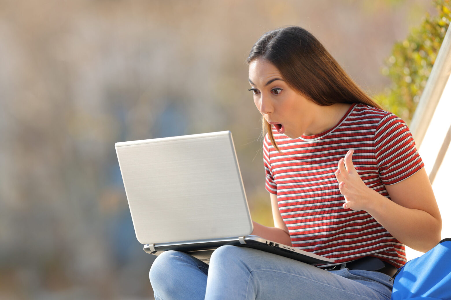 Amazed student checking surprising news on laptop