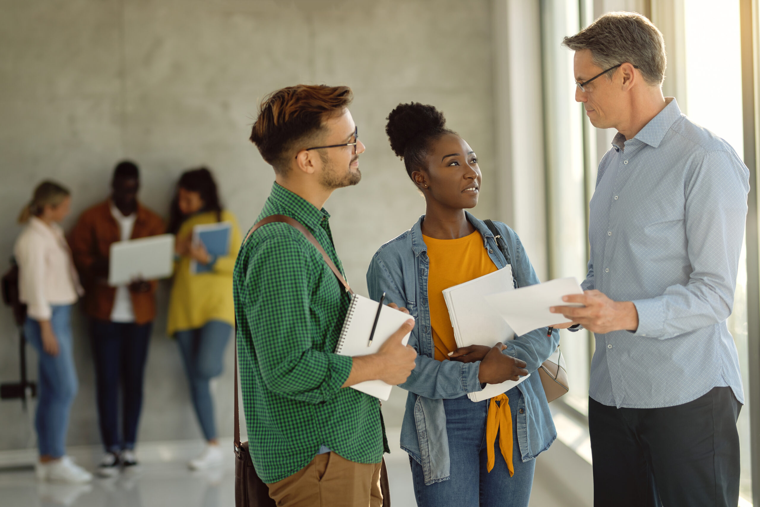 University teacher and his students communicating in a hallway about student loan repayment